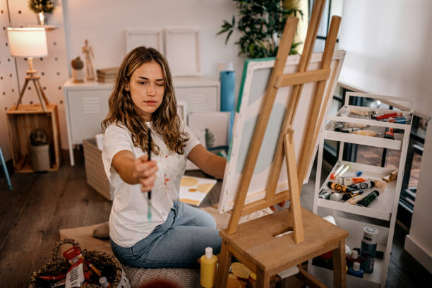 istock Female artist measuring proportion with paintbrush 1360060943