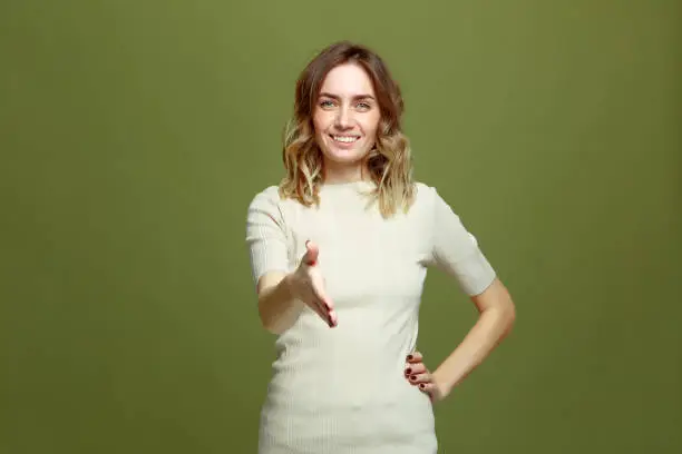 Photo of Smiling young woman offering hand for greeting, handshake, welcoming client or partner. Successful deal, introduction