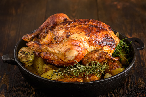 Roasted chicken with potatoes and onions in a cast iron pan