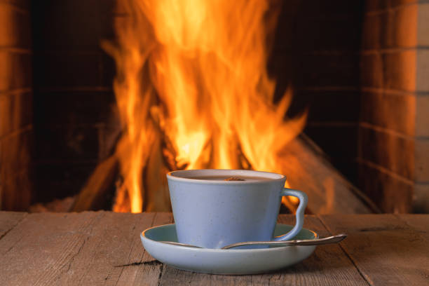 istock Cup of coffee near cozy fireplace background . 1360066606
