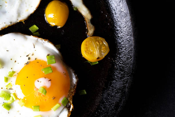 istock breakfast with fried eggs in a pan with bacon and vegetables on dark background 1360067729