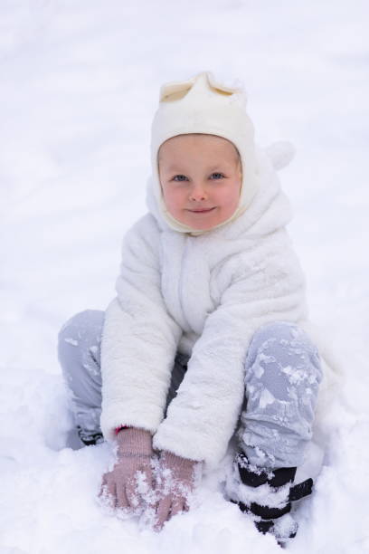 istock Happy girl sitting in snow 1360069612