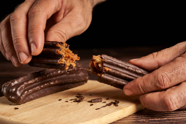 istock hand breaking a churro filled with dulce de leche and dipped in chocolate. 1360071047