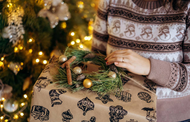 istock Woman s hands wrapping Christmas gift boxes, close up. Unprepared presents on white table with decor elements and items Christmas or New year DIY packing Concept. 1360073353