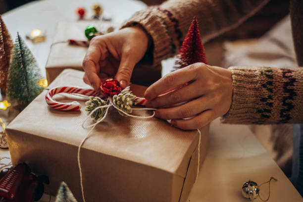 istock Woman s hands wrapping Christmas gift boxes, close up. Unprepared presents on white table with decor elements and items Christmas or New year DIY packing Concept. 1360073383