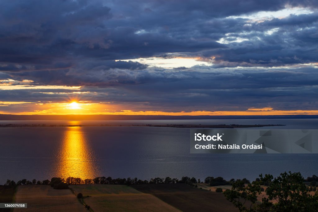 Sunset on the Lake Vättern in Sweden Dark blue clouds, golden sun Beach Stock Photo