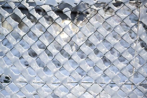 istock Chain link fence from wire mesh covered with snow, abstract winter texture background, concept for weather, nature and season, selected focus 1360077454