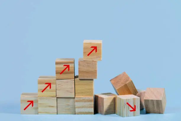 Collapsed stair structure of wooden cubes with upward pointing arrows, business risk due to inflation, global crisis, supply shortage or unsustainable financial concept, light blue background with copy space, selected focus