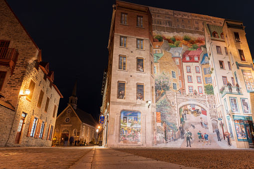 Quebec, Canada - October 18 2021 : Fresco Wall Art in the Quebec City Old Town in autumn night. Mural of Quebecers.