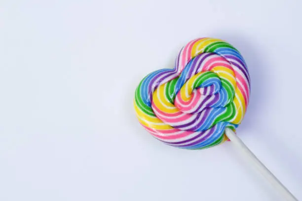 A lollipop on white background. have colors like a rainbow, heart shape.