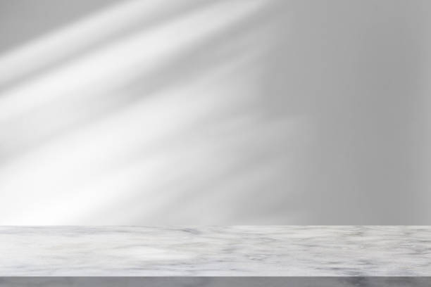 istock Marble table with window shadow drop on white wall background for mockup product display 1360089496