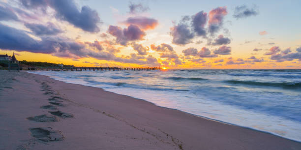 istock Beautiful sunset over the sea, sandy beach with footprints 1360090070