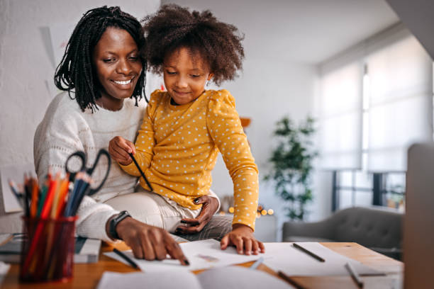 istock Smiling young mother helping daughter with studies and drawing 1360090324