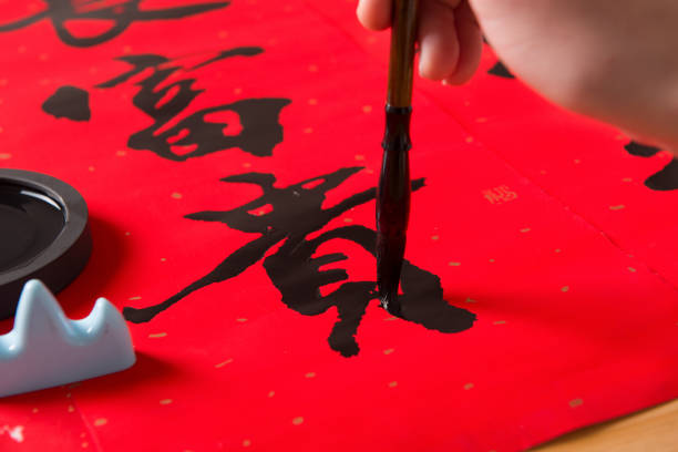 primer plano de escribir coplas del festival de primavera para celebrar las vacaciones del año nuevo chino. - chinese script fotografías e imágenes de stock