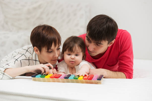 Happy young family with baby girl playing xylophone toy stock photo