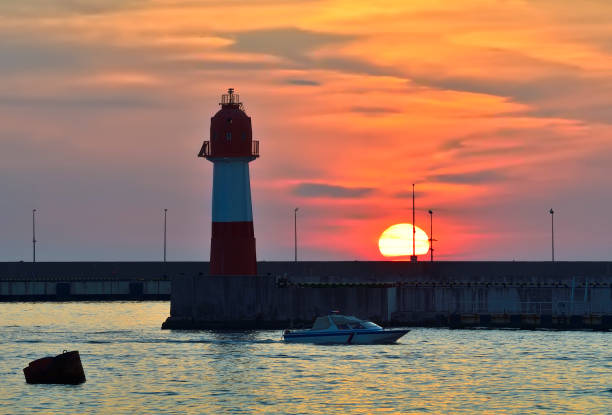 istock Boat at the sea lighthouse at sunset. 1360111971