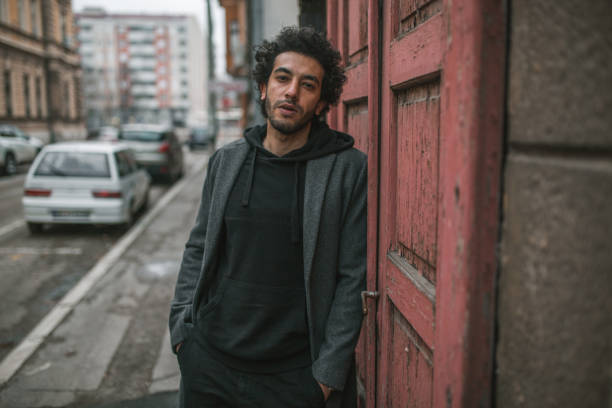 istock Handsome man standing leaning against a door with his hands in his pockets 1360112576