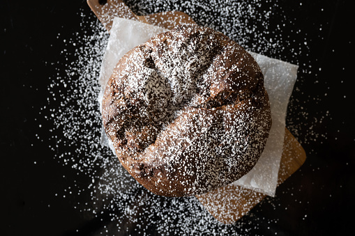 Panettone with power sugar sugar on a black background with copy space