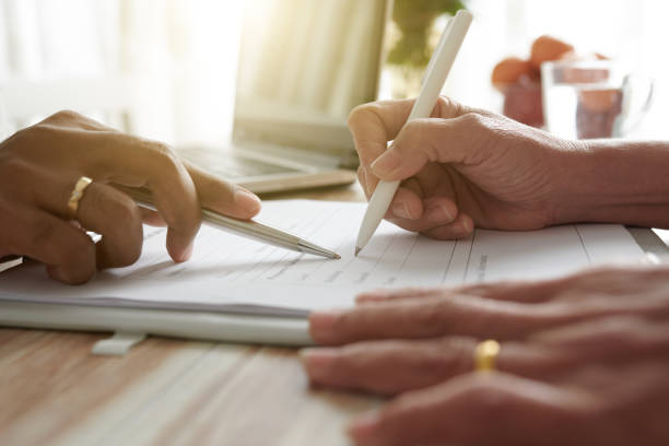 istock Senior Woman Signing Document 1360124289