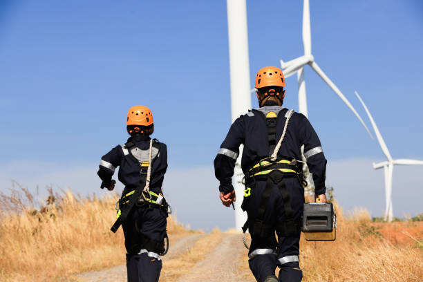istock Young maintenance engineer team working in wind turbine farm , Technician and Engineer wearing safety  harness PPE working at Wind Turbine farm 1360124572