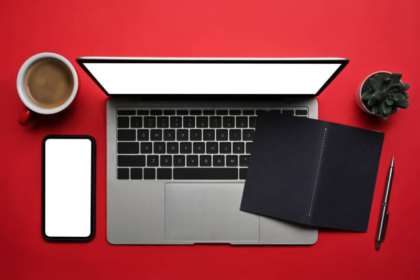 istock Above view laptop computer, smart phone, coffee cup and notebook on red background. 1360125189
