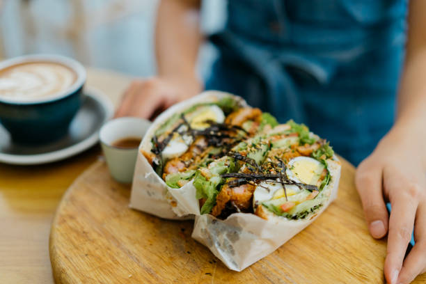 jeune femme asiatique prenant un sandwich et un café au café - freedom sandwich bread food photos et images de collection