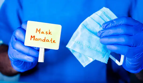 Photo of Concept of Mask mandate, Doctor Showing Mask with Mask mandate sign board to protect against coronavirus or covid-19 pandemic at hopsital.