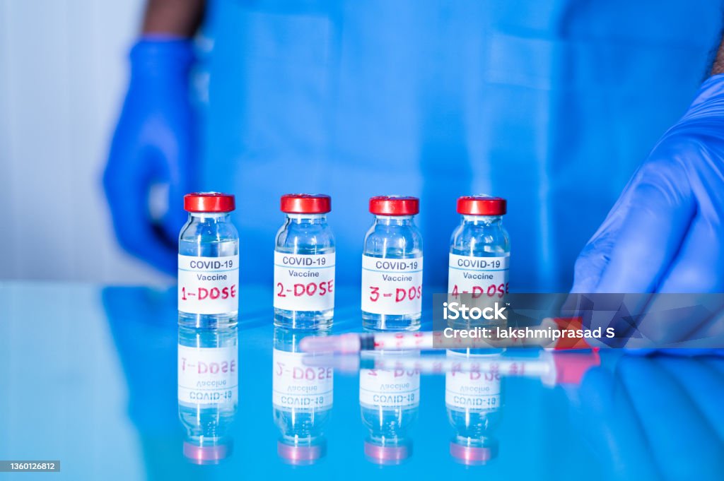 Close up of doctor placing multiple doses of covid-19 or coronavirus vaccine and syringe on table for vaccination to protect againt coronavirus variants or to stop pandemic Close up of doctor placing multiple doses of covid-19 or coronavirus vaccine and syringe on table for vaccination to protect against coronavirus variants or to stop pandemic. Number 4 Stock Photo