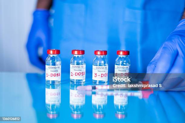 Close Up Of Doctor Placing Multiple Doses Of Covid19 Or Coronavirus Vaccine And Syringe On Table For Vaccination To Protect Againt Coronavirus Variants Or To Stop Pandemic Stock Photo - Download Image Now