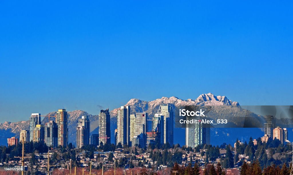 New Residential Area in Burnaby City New residential area of  high-rise buildings in the city of Burnaby, construction site in the center of the city against the backdrop of snow covered mountain range and blue sky British Columbia Stock Photo