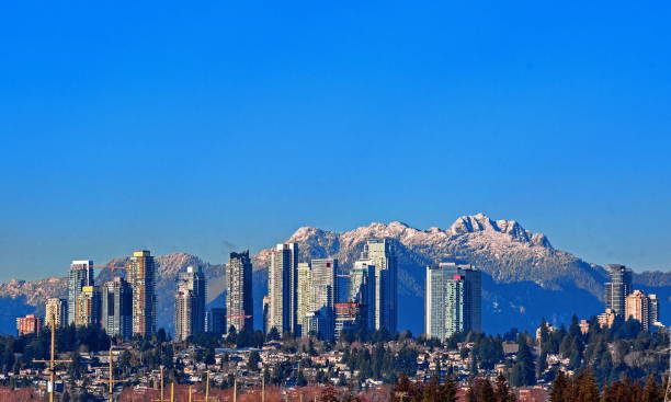 New Residential Area in Burnaby City New residential area of  high-rise buildings in the city of Burnaby, construction site in the center of the city against the backdrop of snow covered mountain range and blue sky british columbia stock pictures, royalty-free photos & images