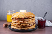 Stack of freshly baked pancakes with butter, honey and jam.