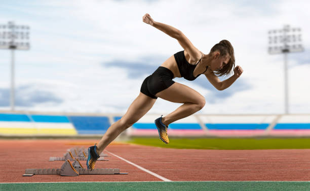 istock Woman sprinter leaving starting blocks on the athletic track 1360131402