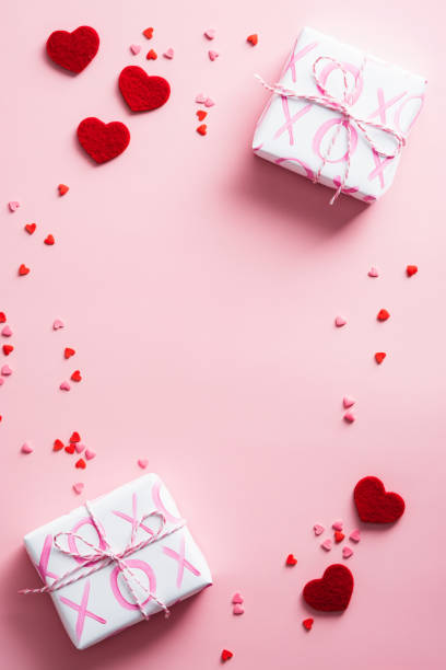 istock Gift boxes and red hearts decorations on pink table. Happy Valentines Day vertical background. Flat lay. Top view. 1360133892