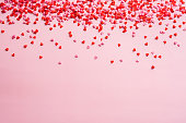 ピンクの背景に赤とピンクの小さなハートの装飾。バレンタインデーフレームボーダー。愛、ロマンスの概念。