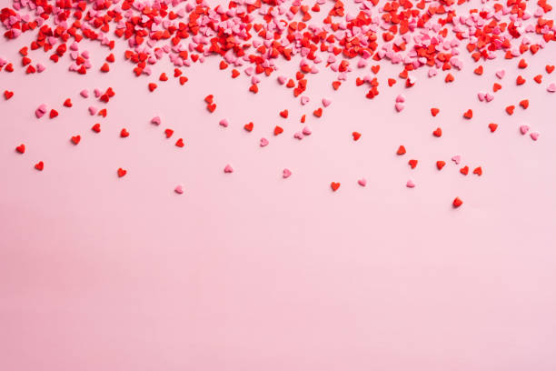 red and pink small hearts decorations on pink background. valentines day frame border. love, romance concept. - heart shape confetti small red imagens e fotografias de stock