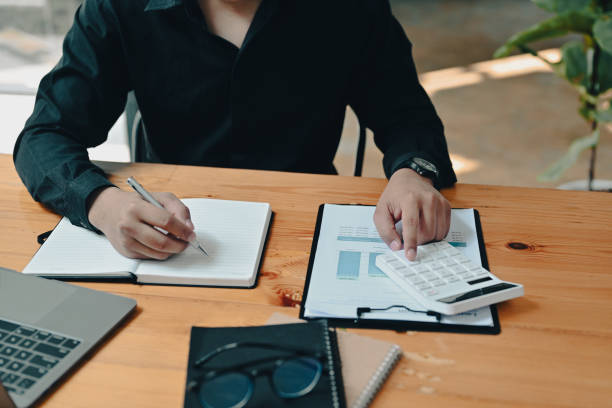 istock Male accountant using calculator and working with laptop at office. 1360139190