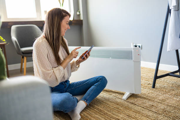 istock Woman using a home control centre on her phone to turn the heating on. 1360143126