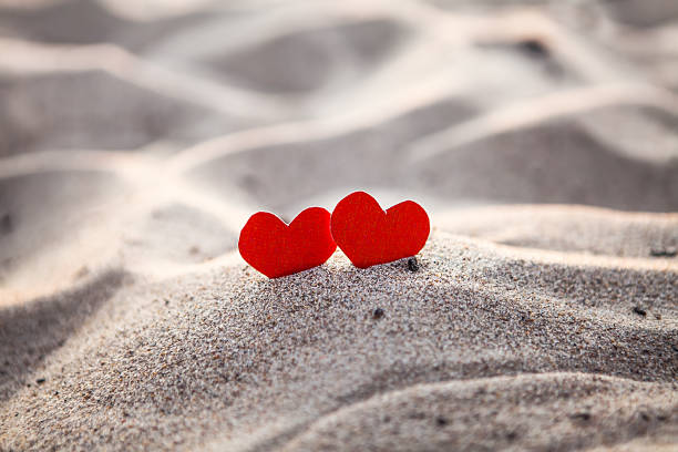 istock Two Heart Shapes on the Sand 1360144984