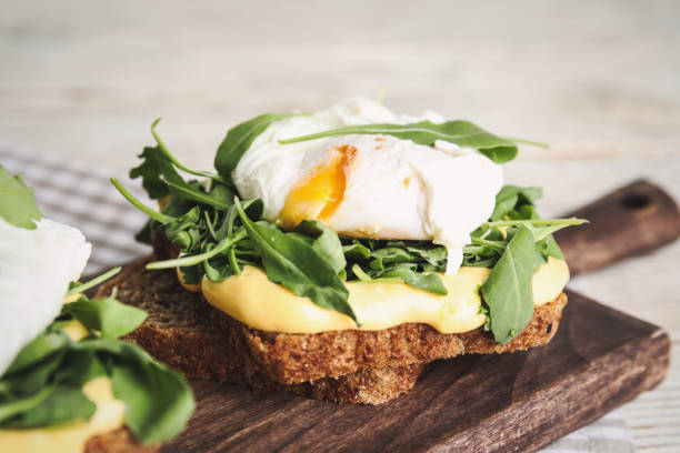 istock Delicious sandwich with arugula and egg on wooden board, closeup 1360145975
