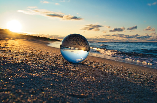 Glass globe on the beach of the Baltic Sea in Zingst in which the landscape is depicted.