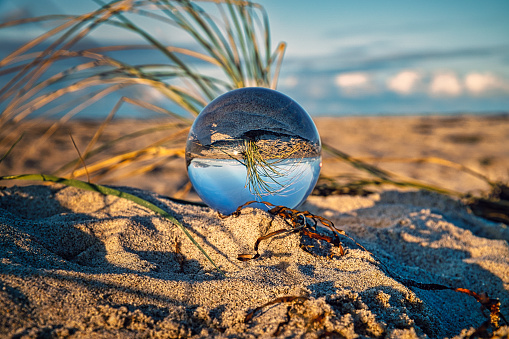Glass globe on the beach of the Baltic Sea in Zingst in which the landscape is depicted.