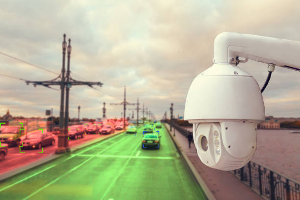 istock The concept of video surveillance and security technology. A surveillance camera monitors the violators of traffic rules. In the background, the road of different congestion, red and green colors 1360147668