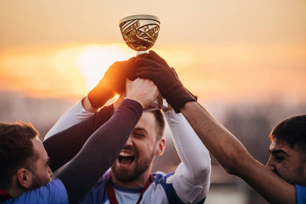 Football team won a trophy Group of people, male soccer players celebrating because they won a trophy, on a soccer field on winter day outdoors. medallist stock pictures, royalty-free photos & images