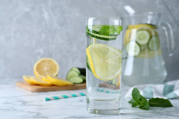 istock Refreshing water with cucumber, lemon and mint on white marble table. Space for text 1360147926
