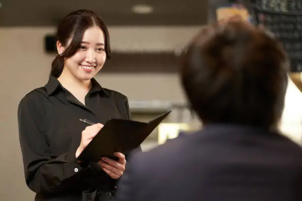 Photo of Asian female taking an order at a restaurant