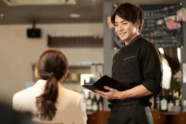 Photo of Asian man taking an order at a restaurant