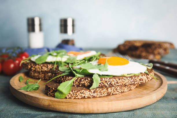 istock Delicious sandwiches with arugula and fried egg on blue wooden table 1360148792