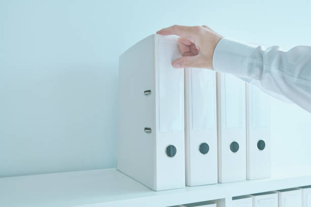 istock Accountant bookkeeper reaching for document ring binder from the office shelf 1360148992