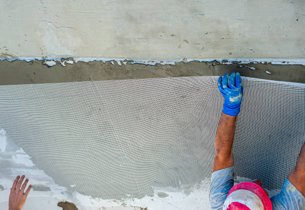 pracownik budowlany nakłada siatkę z włókien wzmacniających wraz z zaprawą tiksotropową na ścianę z uszkodzeniami strukturalnymi - trowel power concrete finishing zdjęcia i obrazy z banku zdjęć